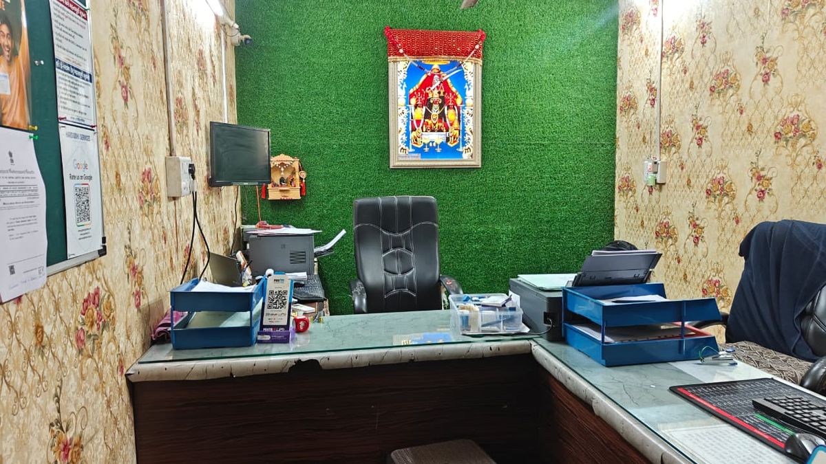The front desk at Harsiddhi Services with document trays, printer and the Google review QR code on the wall.