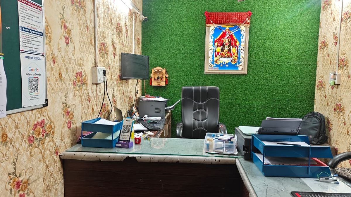 Inside the Harsiddhi Services office: work stations, printers and document trays on a working day.